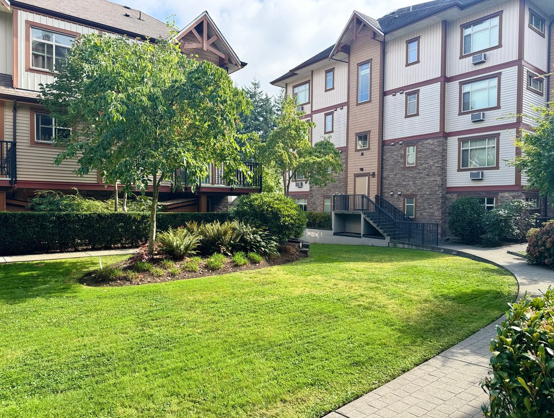 Mown lawn, ornamental trees and shrub beds at an apartment complex